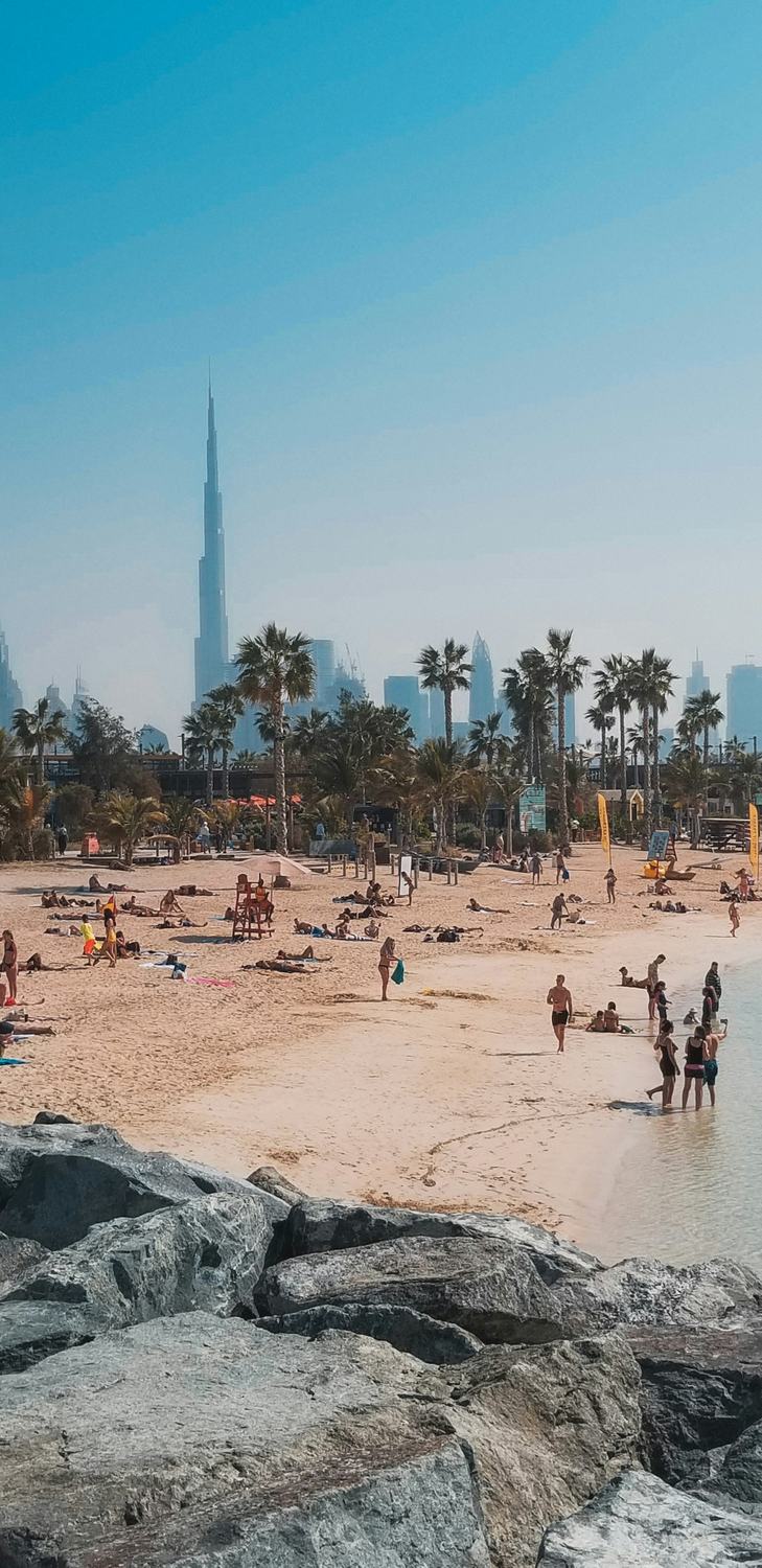 People on the beach at JBR with the Dubai skyline behind