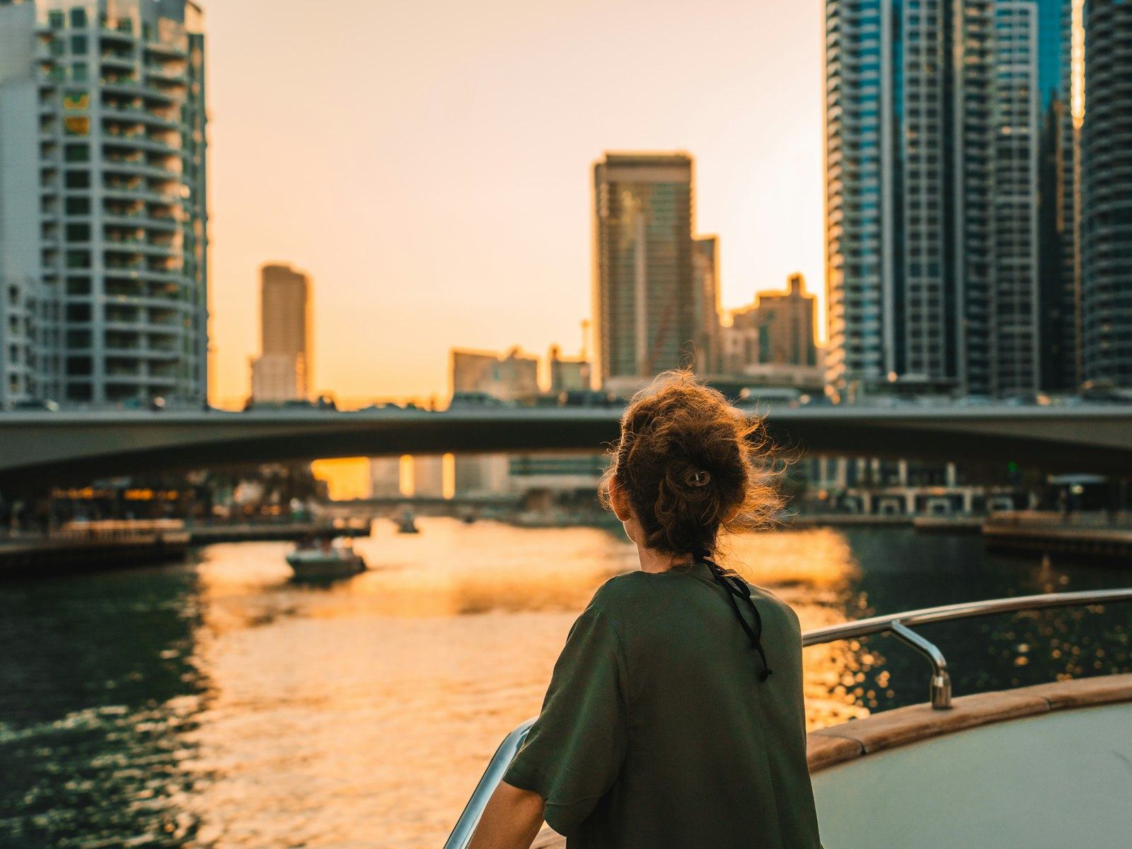 A woman on a boat looking at the Dubai Marina skyline at sunset